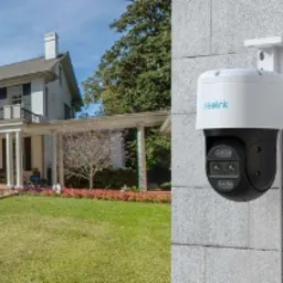 Zewnętrzna, obrotowa kamera IP Reolink z podwójnym obiektywem, zamontowana na elewacji budynku, z widokiem na dom z ogrodem.