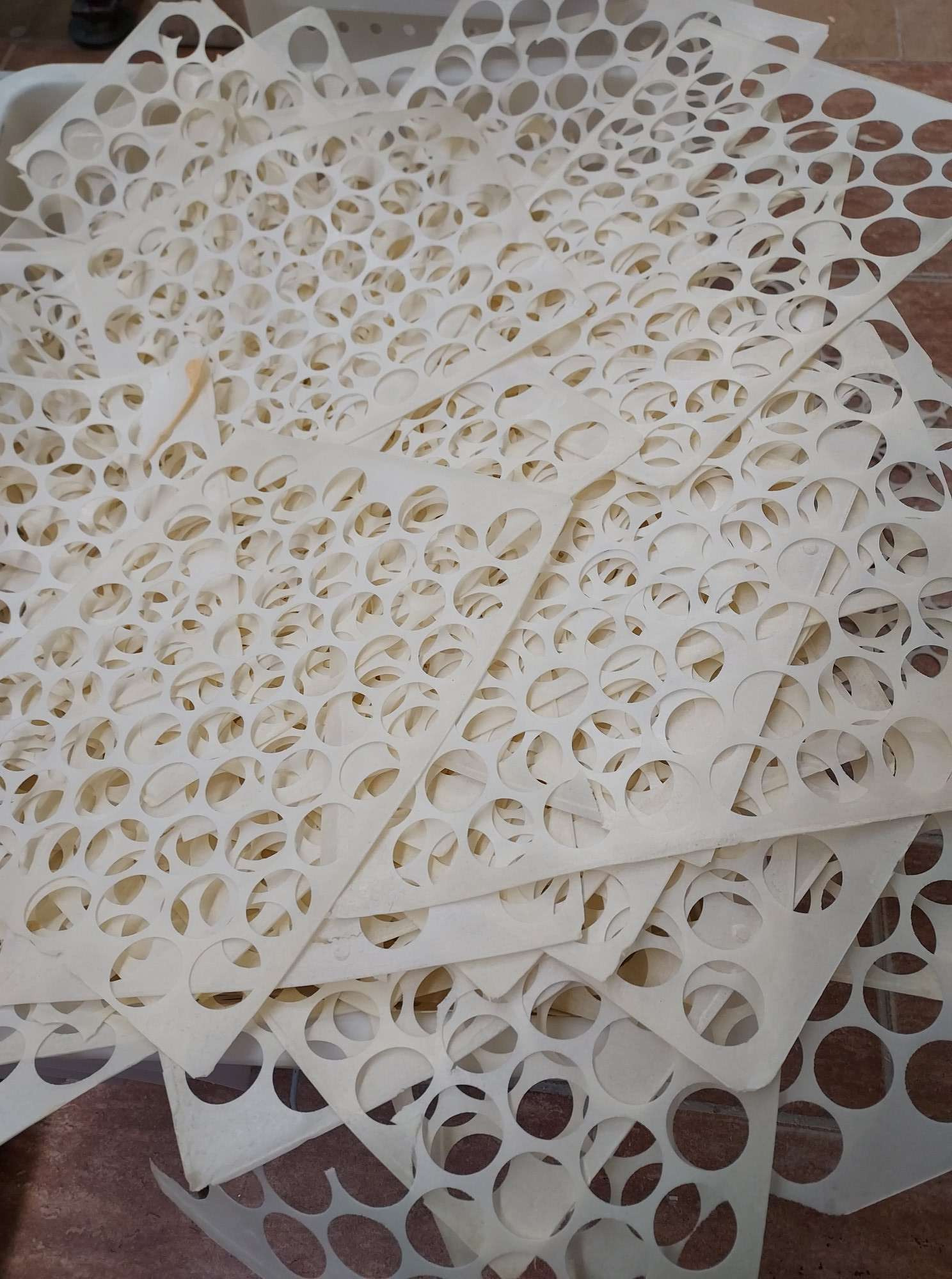 Stos arkuszy z perforowanymi okręgami na brązowej powierzchni, widoczne ślady użytkowania.