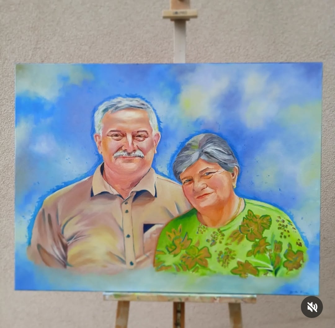 Portret olejny starszego małżeństwa na płótnie, umieszczony na drewnianej sztaludze; pastelowe tło w odcieniach błękitu i bieli.