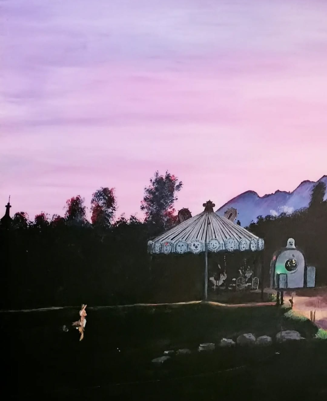 Obraz przedstawiający karuzelę z motywami twarzy pod fioletowym niebem o zmierzchu, z sylwetkami drzew i gór w tle, oraz figurką królika w lewym dolnym rogu.