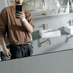 Autoportret instalatora w łazience z zamontowanymi umywalkami, widoczne drabiny, narzędzia i lustrzane odbicie wnętrza w trakcie prac wykończeniowych.