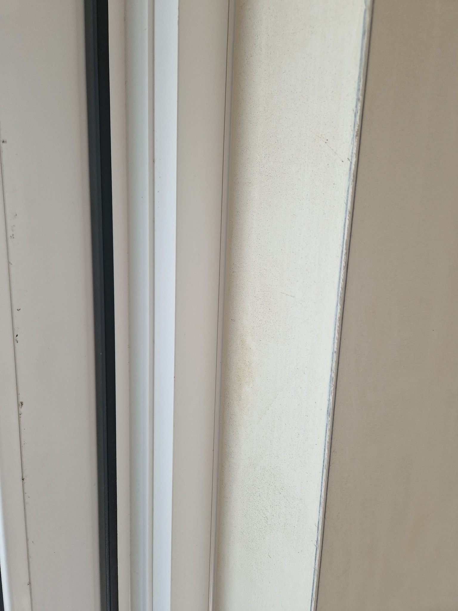 Fragment ściany z widocznym łączeniem płyt kartonowo-gipsowych przed szpachlowaniem, z widocznymi śladami po taśmie wzmacniającej i miejscowymi niedoskonałościami powierzchni.