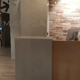 Recepcja w nowoczesnej kancelarii z ceglaną ścianą, szklanymi drzwiami z logo i minimalistycznym wystrojem.