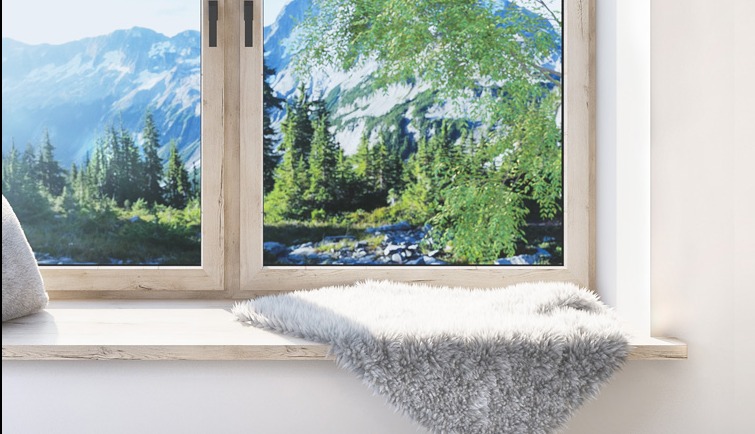 Okno PCV z widokiem na górski krajobraz, parapet zdobi miękki, biało-szary pled.