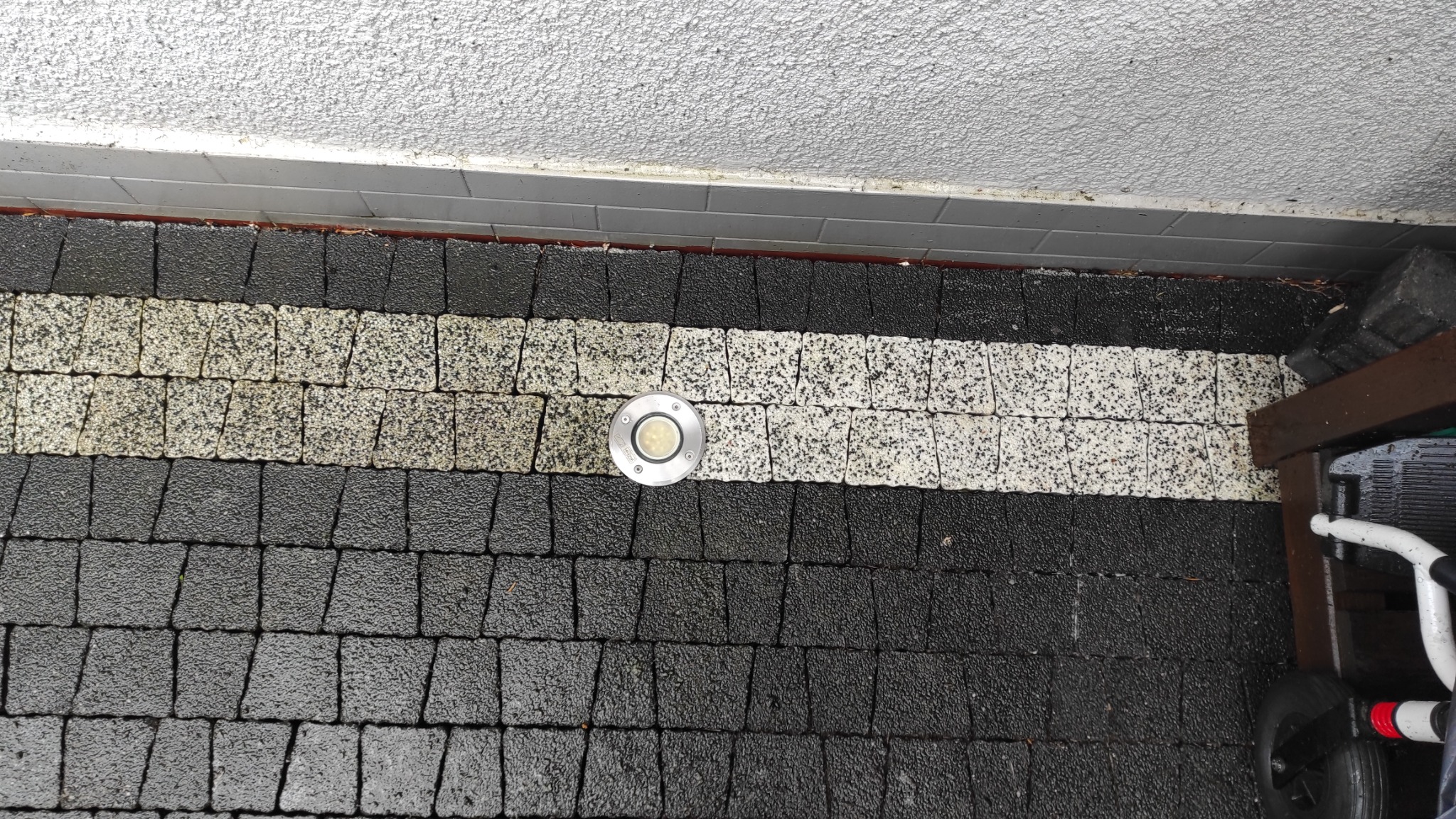 Ułożona kostka brukowa w kolorach czerni i bieli z wbudowanym oświetleniem punktowym, widok z góry na fragment tarasu.