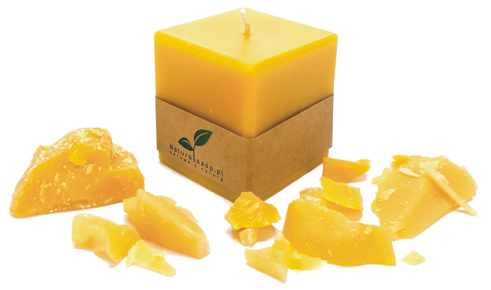 Żółta, kwadratowa świeca z wosku pszczelego z brązową etykietą, otoczona kawałkami surowego wosku na białym tle.