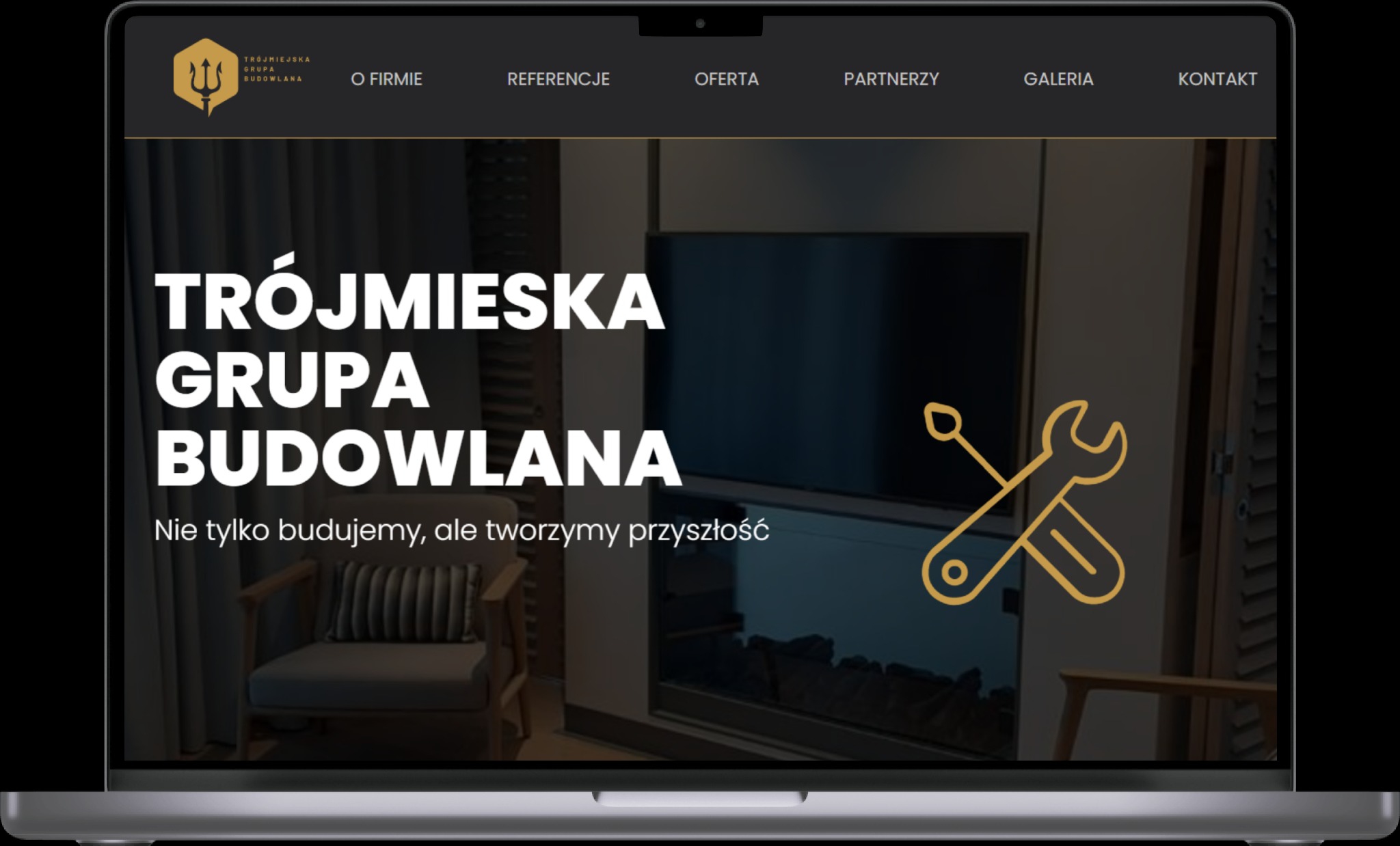 Ekran laptopa wyświetlający stronę internetową firmy budowlanej Trójmiejska Grupa Budowlana, z logo firmy w lewym górnym rogu i menu nawigacyjnym u góry. W tle widoczny fragment wnętrza z fotelem...