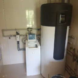 Zamontowana instalacja z pompą ciepła Buderus i systemem uzdatniania wody BWT w pomieszczeniu z beżowymi płytkami.