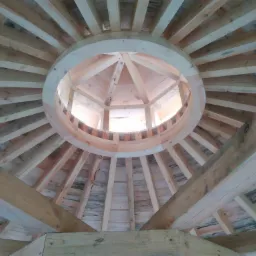 Wnętrze kopuły w trakcie budowy, widok od dołu, ukazujący drewnianą konstrukcję szkieletową z okrągłym otworem w centrum.