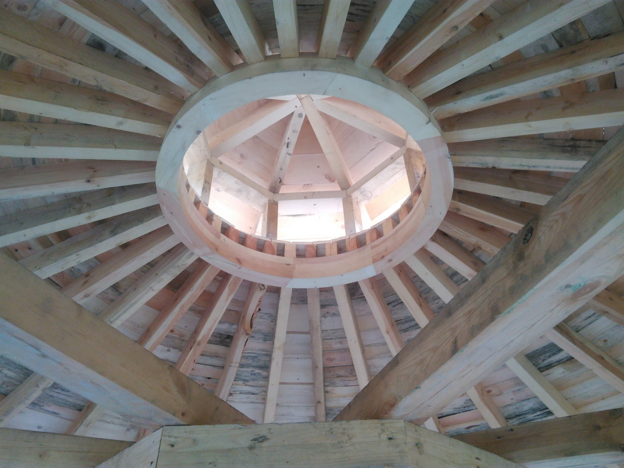 Wnętrze kopuły w trakcie budowy, widok od dołu, ukazujący drewnianą konstrukcję szkieletową z okrągłym otworem w centrum.