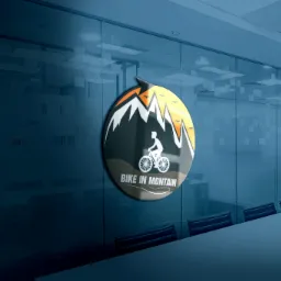 Mockup logo firmy rowerowej 'Bike in Montain' umieszczone na szklanej ściance w biurze, widok z perspektywy stołu konferencyjnego.