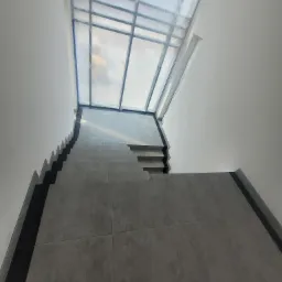 Wykończone schody z szarych płytek prowadzące w dół, widok z góry, z okienkiem dachowym zabezpieczonym folią malarską.