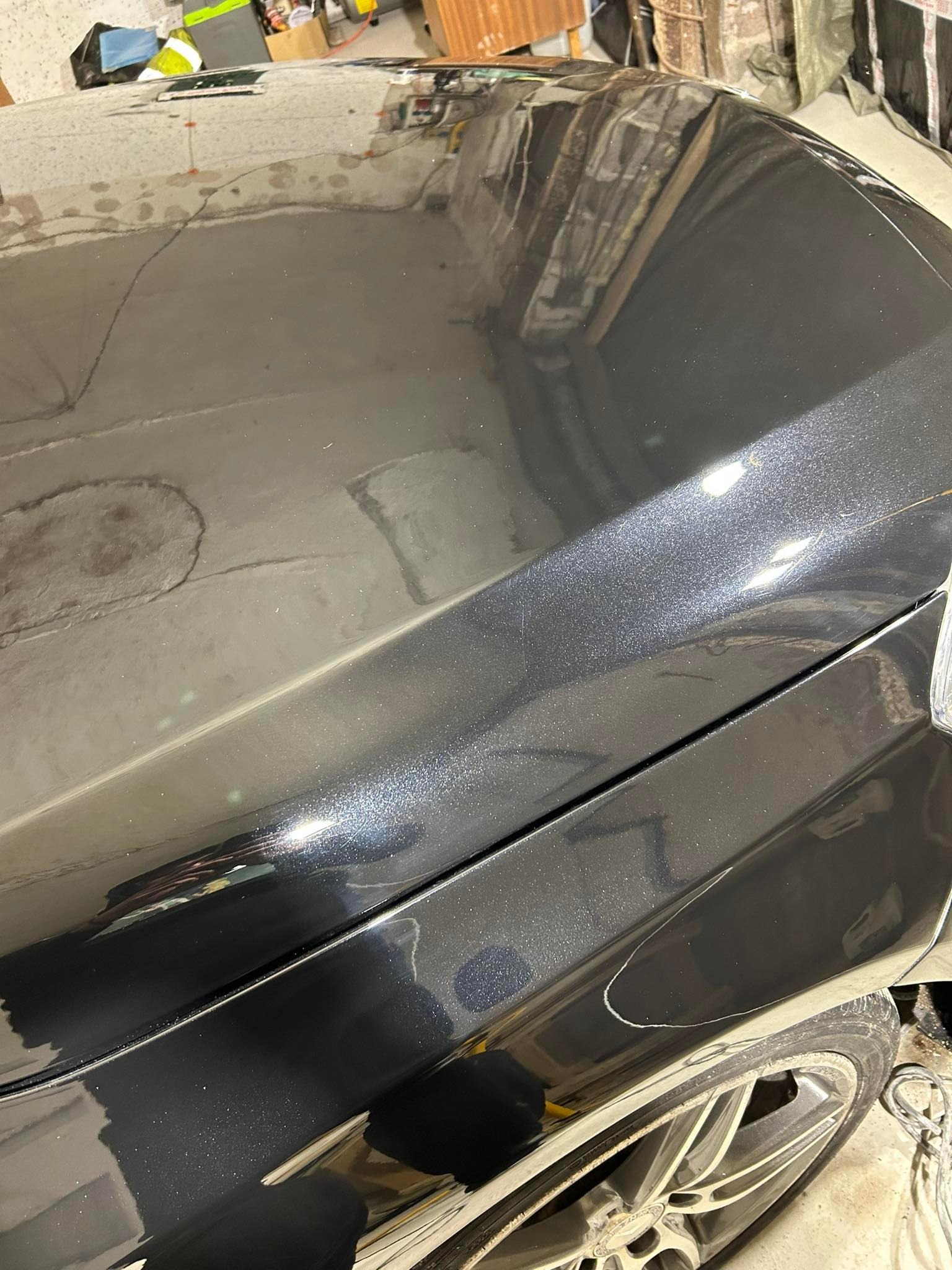 Fragment karoserii czarnego samochodu z widocznymi śladami po polerowaniu i brudnymi felgami.