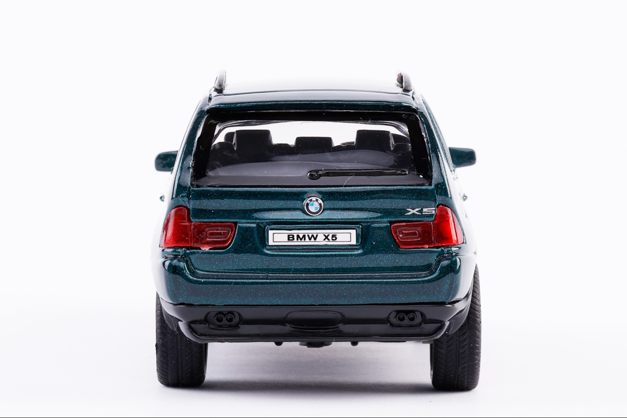 Szczegółowe ujęcie od tyłu zielonego modelu BMW X5 na białym tle, ukazujące detale karoserii, lamp i tablicy rejestracyjnej.