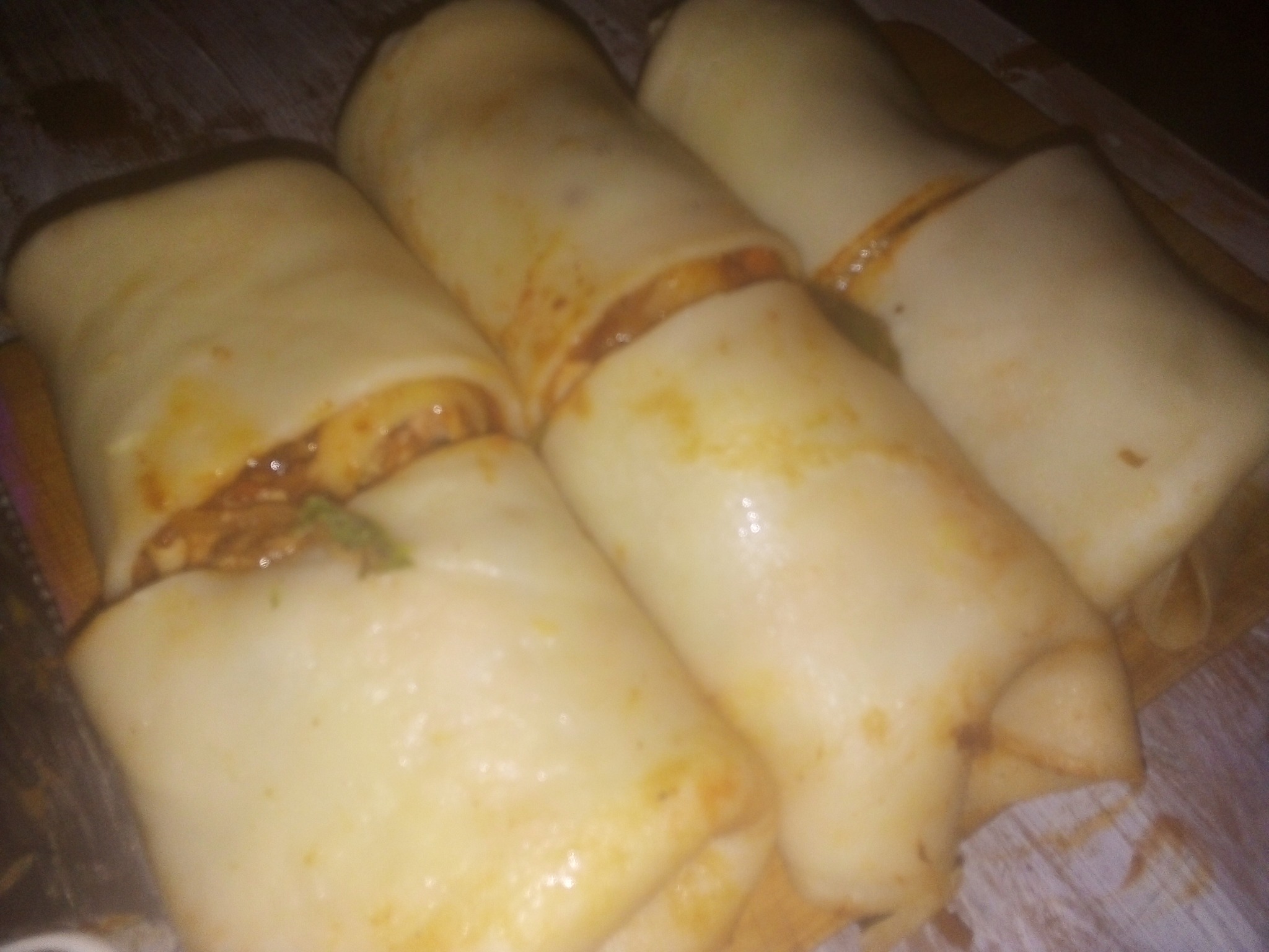 Roladki z farszem, prawdopodobnie naleśnikowe, ułożone na desce, przygotowane przez firmę z Zielonej Góry.