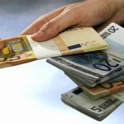 Dwie dłonie wymieniające się plikami banknotów euro o różnych nominałach: 50, 20, 10 i 5 euro, na jasnym, rozmytym tle.