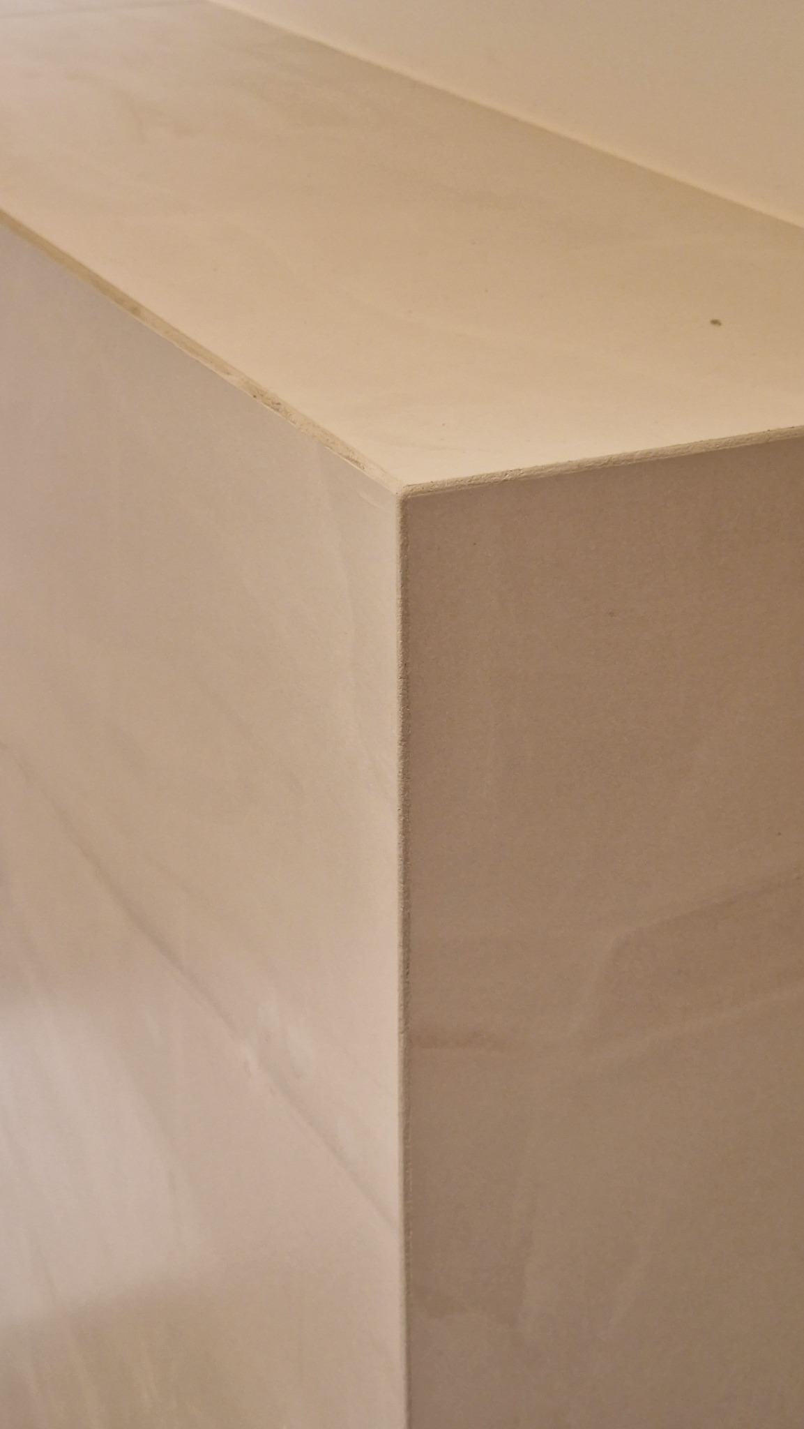 Fragment narożnika ściany po gładziowaniu, widoczne niedoskonałości w fakturze. Jasny odcień gładzi.