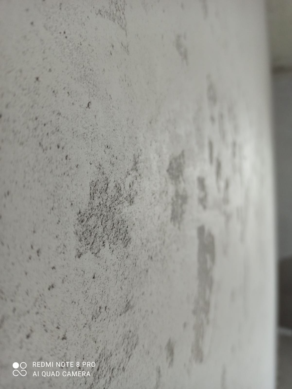 Surowa, szpachlowana ściana z widoczną fakturą i nierównościami, przygotowana do dalszych prac wykończeniowych.