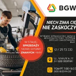 Mechanik w szarym kombinezonie roboczym montuje nową oponę na maszynie wulkanizacyjnej; w tle logo i dane kontaktowe serwisu BGW.