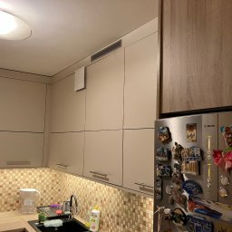 Meble Paweł Król - Jasna kuchnia z kremowymi szafkami górnymi, mozaikową ścianą nad blatem, czarnym zlewozmywakiem i lodówką Bosch ozdobioną magnesami z podróży.