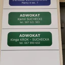 Tablica informacyjna z nazwiskami i numerami telefonów radcy prawnego i adwokatów, umieszczona na ścianie budynku.