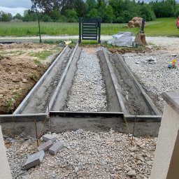 Firma Uslugowa Wojciech Łukaszka - Przygotowanie podłoża pod ścieżkę z kostki brukowej: betonowe obrzeża, podsypka z kamienia, widok z perspektywy ułożonej kostki przy wejściu do domu.