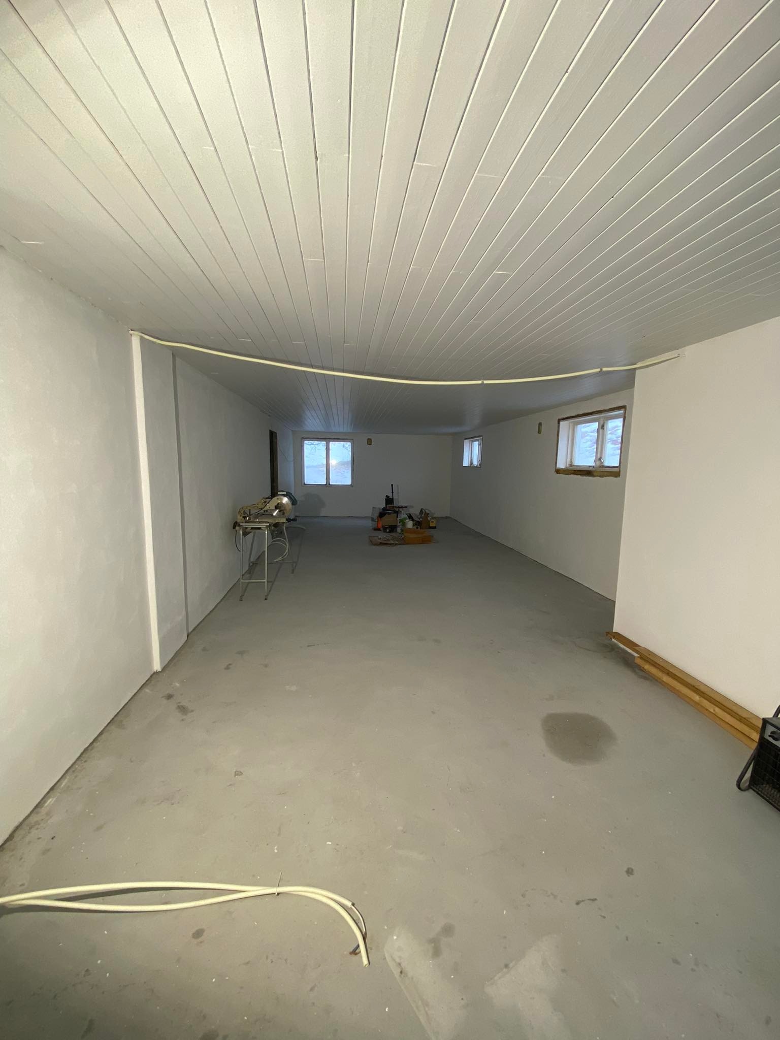 Wnętrze pomieszczenia we Wrocławiu w trakcie prac przygotowawczych: surowe ściany po szpachlowaniu, widoczny sprzęt budowlany i materiały, przygotowane do dalszych prac wykończeniowych.