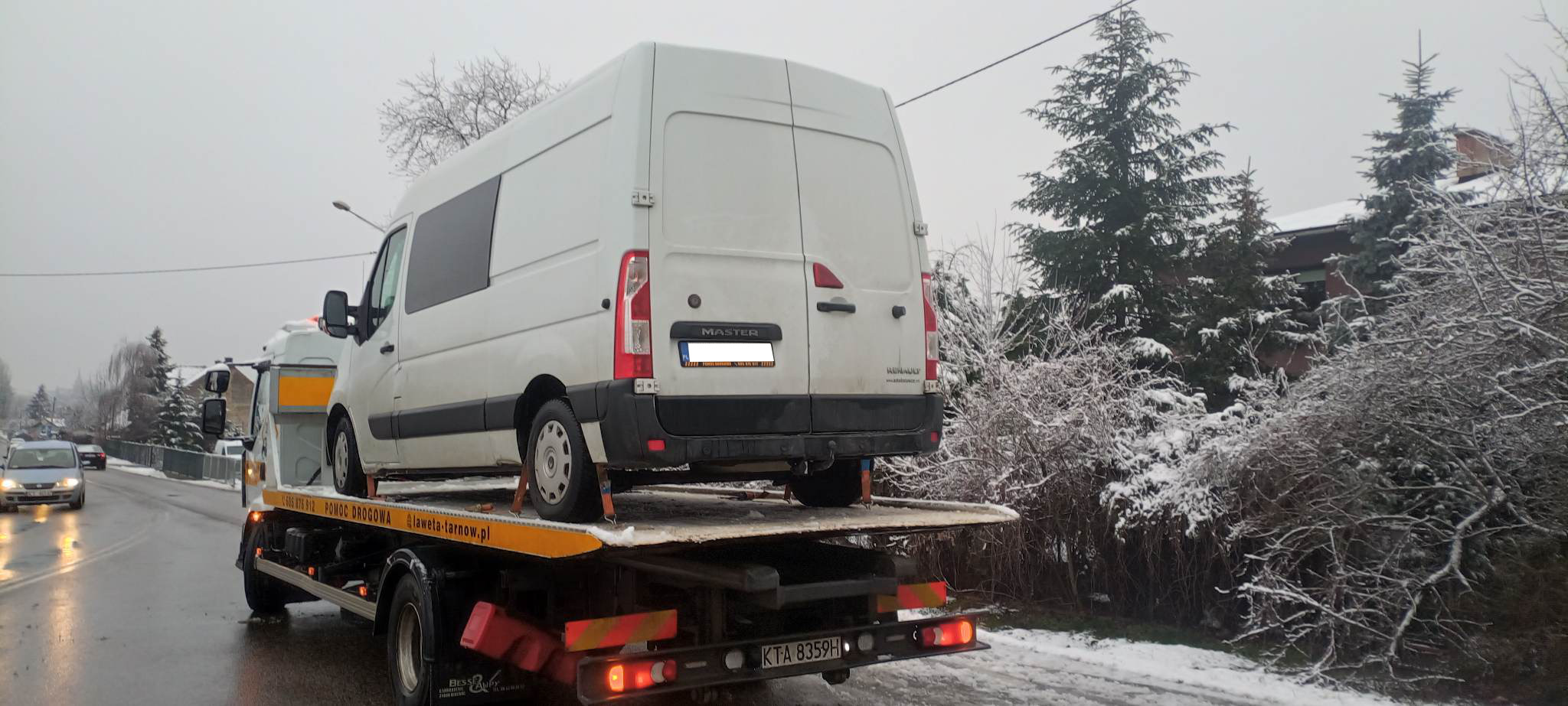 Biały bus Renault Master przewożony na lawecie w zimowej scenerii, widok z tyłu, tablica rejestracyjna KTA 8359H.