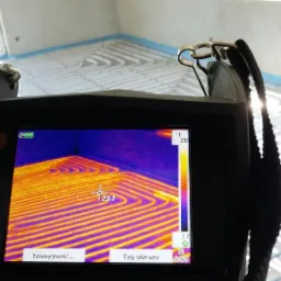 Kamera termowizyjna marki Testo, ukazująca rozkład temperatur na rurach ogrzewania podłogowego, z widoczną wartością 23.7 stopni Celsjusza w centralnym punkcie ekranu.