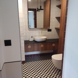 Volodymyr Gonchar - Nowoczesna łazienka z białą umywalką nablatową, lustrem w drewnianej ramie, czarno-białą szachownicą na podłodze i zabudową z drewnianymi szafkami oraz półkami.