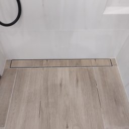 Volodymyr Gonchar - Ukończona łazienka z podłogą imitującą drewno i liniowym odpływem prysznicowym w kolorze czarnym, widok z góry.