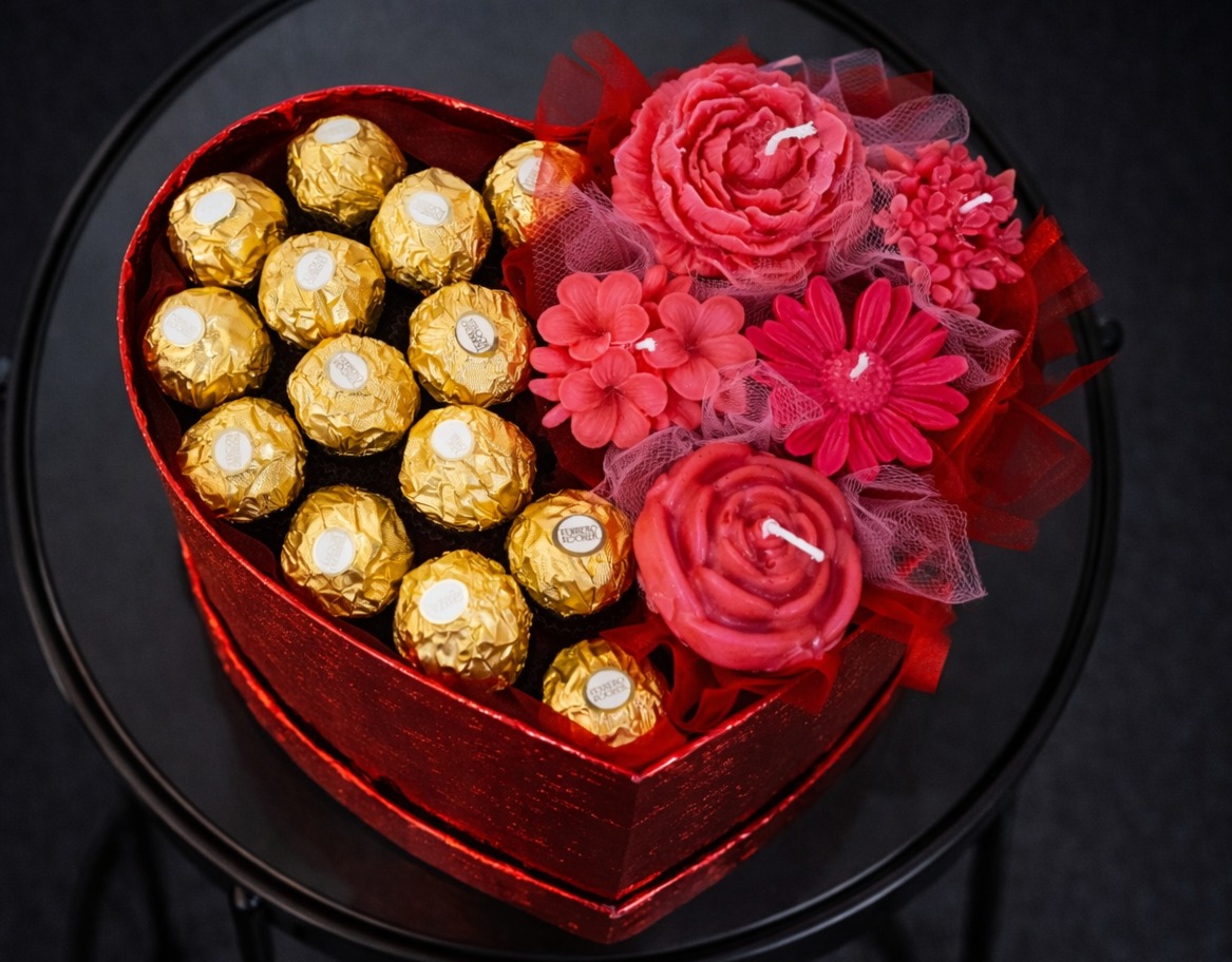 Serce z czekoladek Ferrero Rocher i świec w kształcie kwiatów, prezent na walentynki z Olszanicy, na czarnym stoliku.