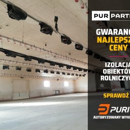 Pur Partner - Biała izolacja pianką PUR na suficie i ścianach wewnątrz budynku gospodarczego z oknami. Widoczne elementy konstrukcyjne i instalacje pod sufitem.