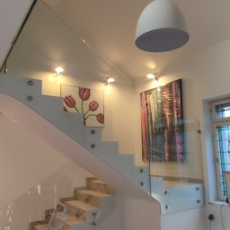 ADIBAU USŁUGI OGÓLNOBUDOWLANE ADRIAN KUBIAK - Montaż szklanej balustrady schodowej z marmurowymi stopniami, widoczny aluminiowy profil i drabina malarska.