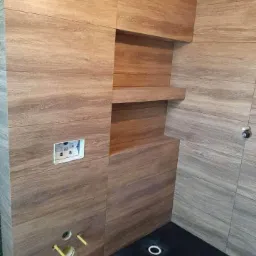 Wykończona łazienka w Przedborzu z drewnopodobnymi płytkami, czarnym brodzikiem i wnęką z półką.