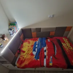 Antresola z wbudowanym łóżkiem dla dziecka, z oświetleniem LED, szafkami i półkami na książki, pościel z motywem Zygzaka McQueen.