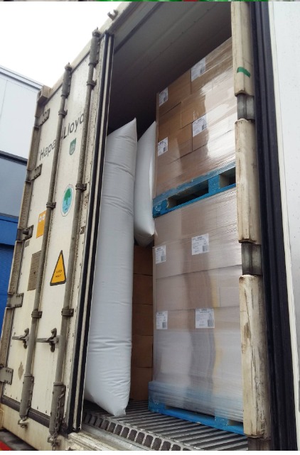 Wnętrze kontenera transportowego Hapag-Lloyd z paletami kartonów zabezpieczonymi poduszkami powietrznymi.