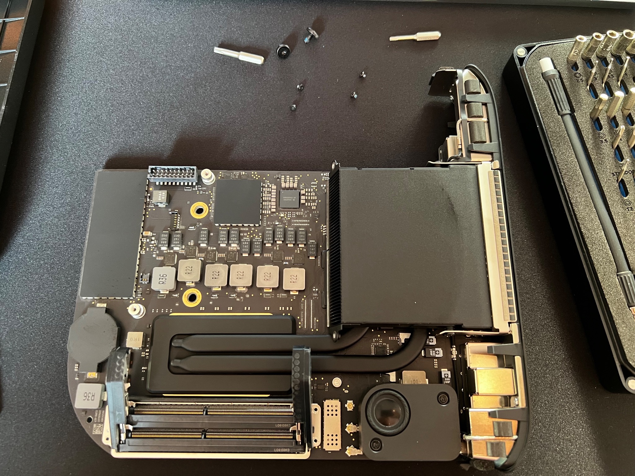 Wnętrze rozmontowanego komputera, widoczna płyta główna z elementami, obok zestaw precyzyjnych śrubokrętów, kilka drobnych śrubek leży obok