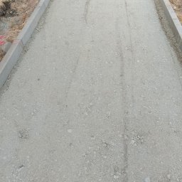 Marbruk - Podbudowa drogi z obrzeżami betonowymi, widok z góry. Przygotowanie podłoża pod nawierzchnię, etap prac ziemnych.