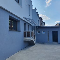 Bud-rem - Budynek po renowacji elewacji w Tarnowskich Górach, z widocznym wejściem z zadaszeniem i świeżo pomalowaną fasadą w odcieniach szarości.