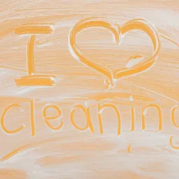 Napis 'I love cleaning' wykonany z piany na pomarańczowej powierzchni.