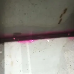 Wewnętrzna powierzchnia metalowej konstrukcji z widocznymi śladami penetrantu w kolorze różowym, używanego do wykrywania wad spawalniczych