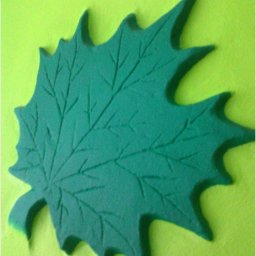 Zibination. Art - Dekoracyjna, trójwymiarowa aplikacja w kształcie zielonego liścia klonu, umieszczona na limonkowym tle ściany, widoczna na zrzucie ekranu z telefonu z komentarzem o 'ciekawych remontach'.