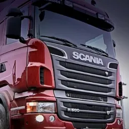 Czerwona ciężarówka Scania R560 z załadowanym drewnem, widok z przodu na tle pochmurnego nieba.