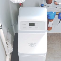 Zmiękczacz wody na cały dom EcoWater Comfort 300. W tle korpusy narurowe na wkłady.