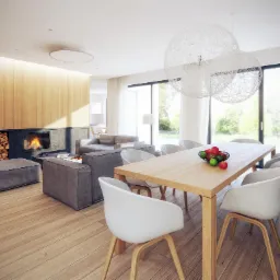 Jasne, przestronne wnętrze salonu z jadalnią, drewniana ściana z kominkiem, minimalistyczne meble, stół z owocami, wiszące lampy kuliste.