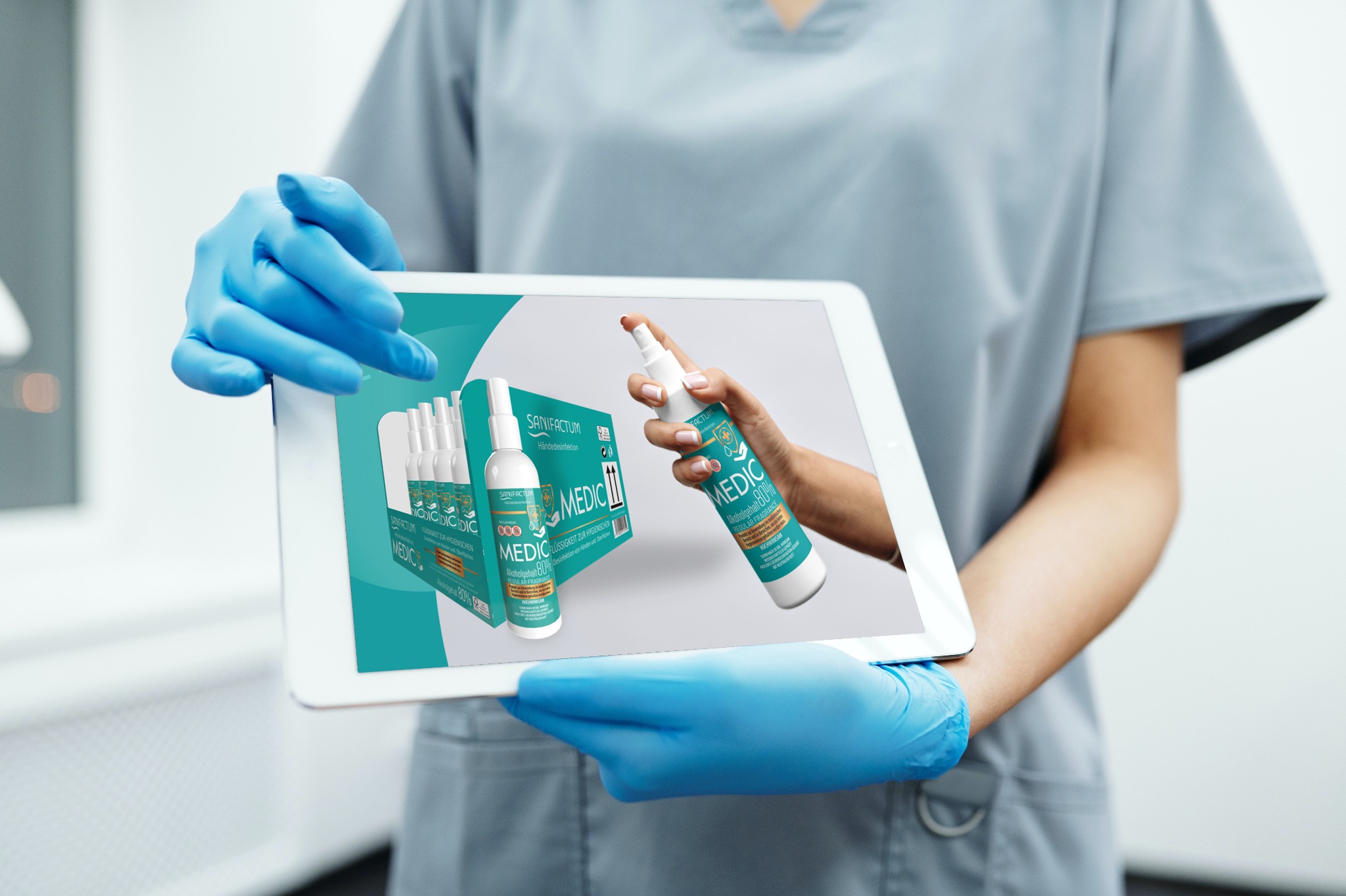 Osoba w niebieskich rękawiczkach prezentuje na tablecie wizualizację produktu Sanifactum Medic, z widocznym opakowaniem zbiorczym i zbliżeniem na butelkę z rozpylaczem.