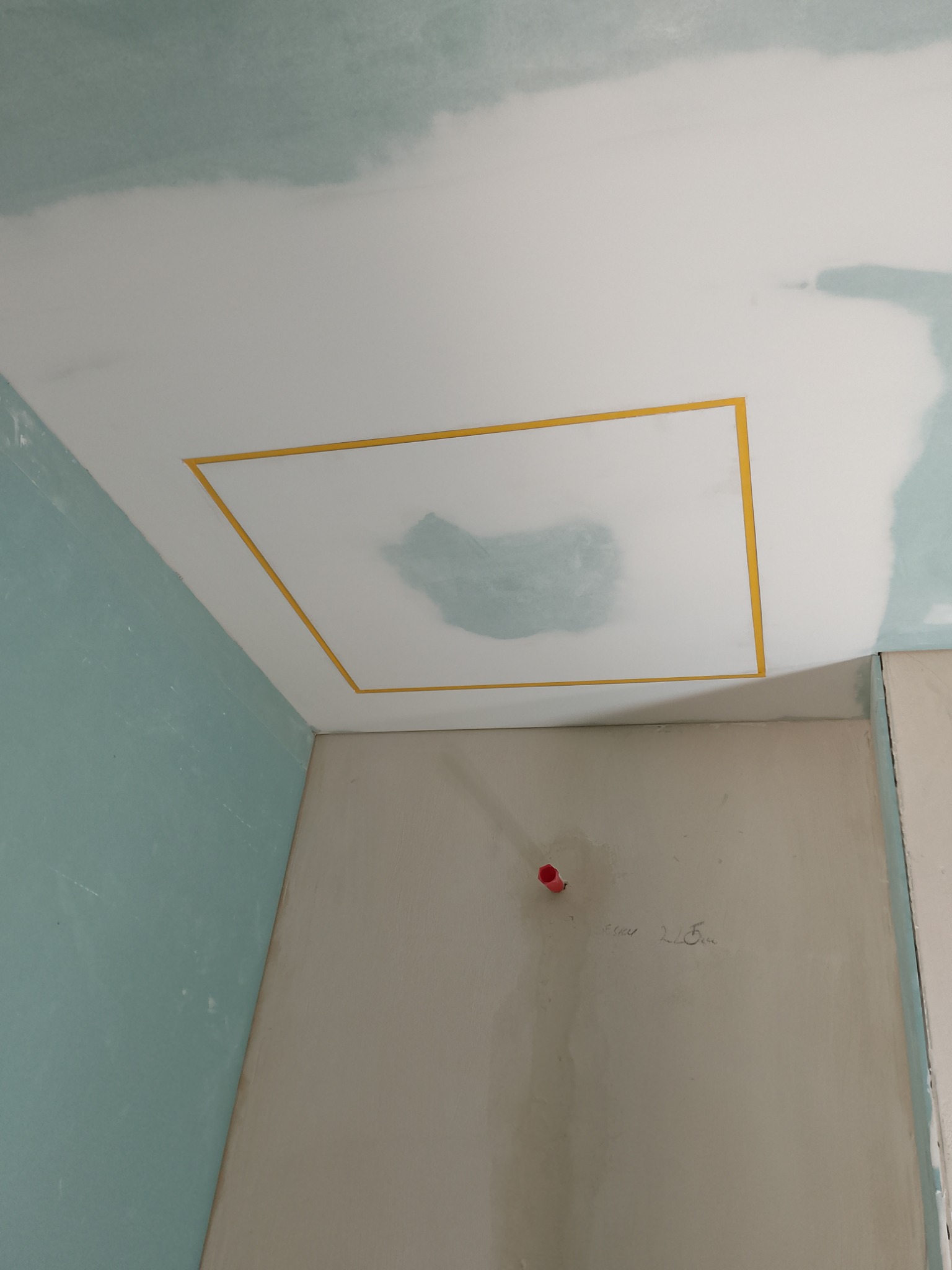 Prace przygotowawcze: sufit z wyciętym otworem, zabezpieczonym żółtą taśmą, ściany w trakcie szpachlowania i malowania. Widoczny fragment instalacji.