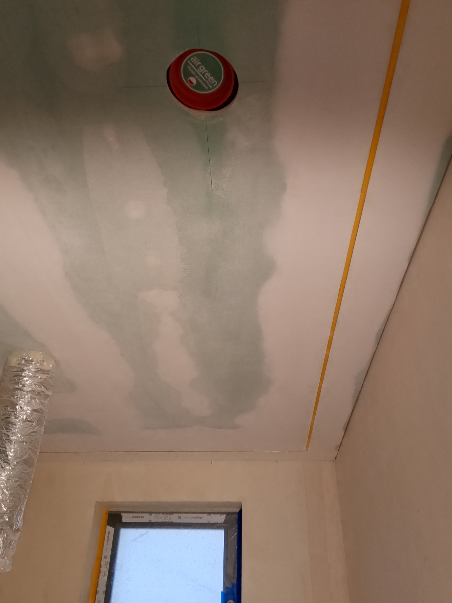 Nierównomiernie nałożona gładź szpachlowa na suficie w Stargardzie, widoczny otwór na oświetlenie z puszką instalacyjną i taśma malarska przy ścianie, przygotowanie do dalszych prac.