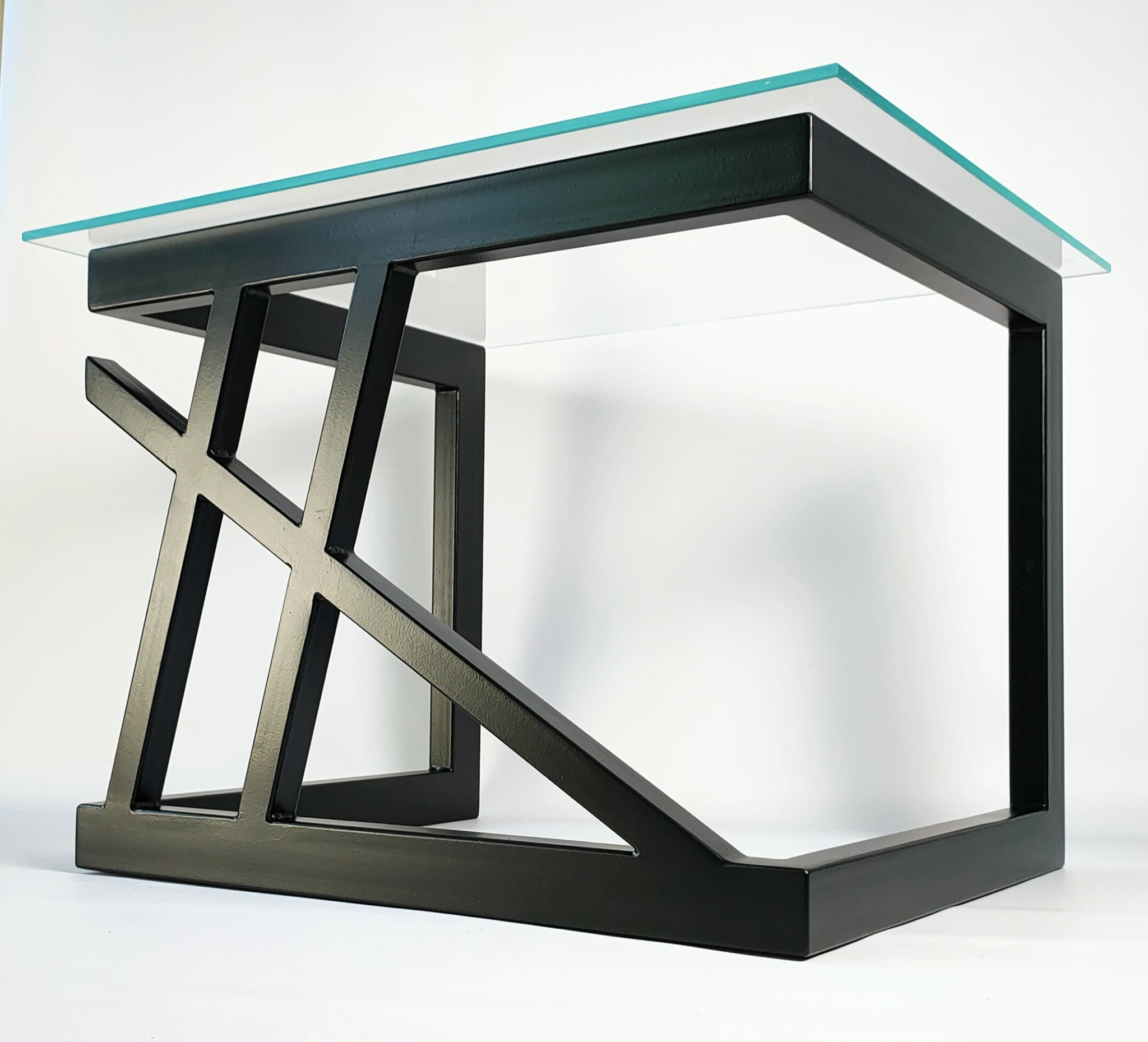 Czarny, metalowy stolik kawowy z geometryczną podstawą i szklanym blatem, sfotografowany na białym tle.